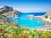 A panoramic view of the clear waters and boats of St. Paul's Bay with Acropolis ruins in background
