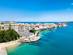 A coastal view of the island of Ortigia in Syracuse, Sicily with white-washed buildings and bright blue sea on a summer's day