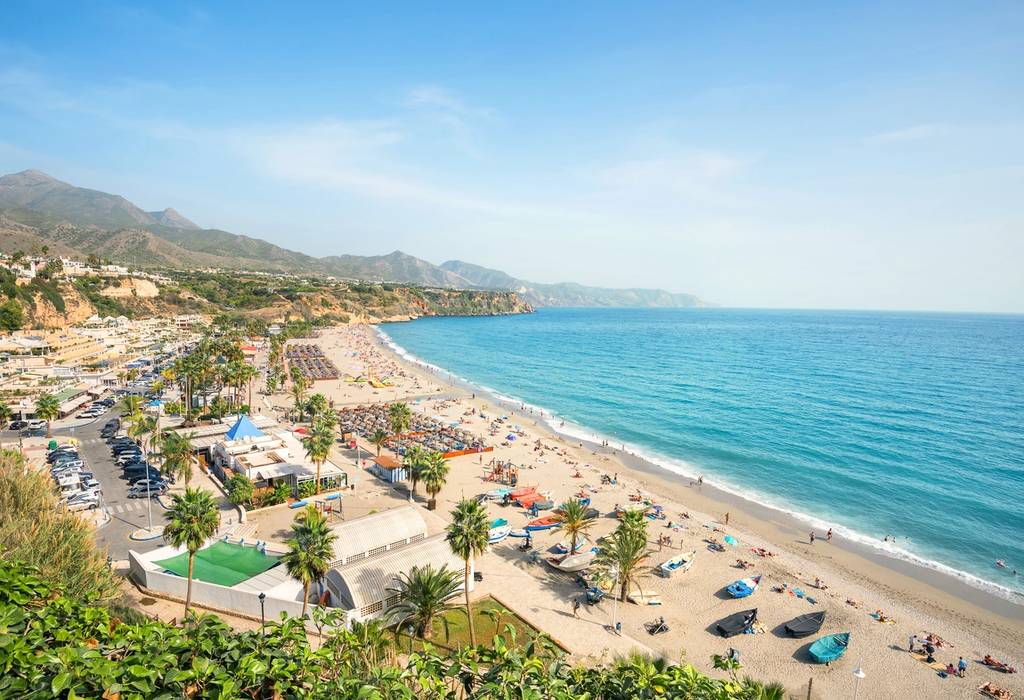 Aerial view of Playa Burriana, a golden beach lined with sun-loungers and palm trees