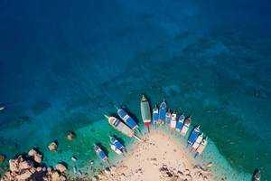Bird's eye view of colourful tourist boats anchored near the small sandy beach of Suluada island in Turkey
