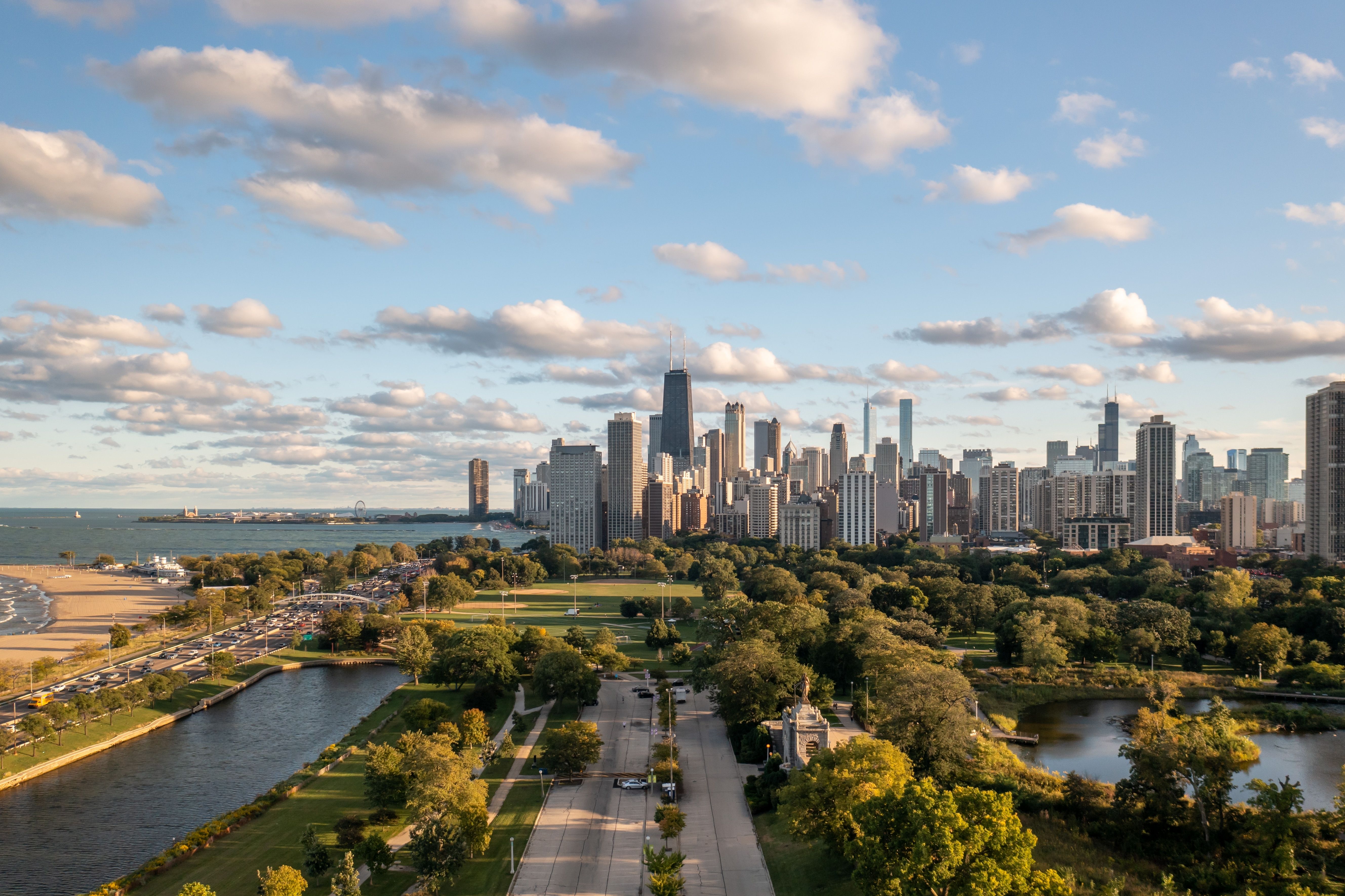 View of a city skyline with skyscrapers in the background and a green spaces with lakes and ponds in the foreground