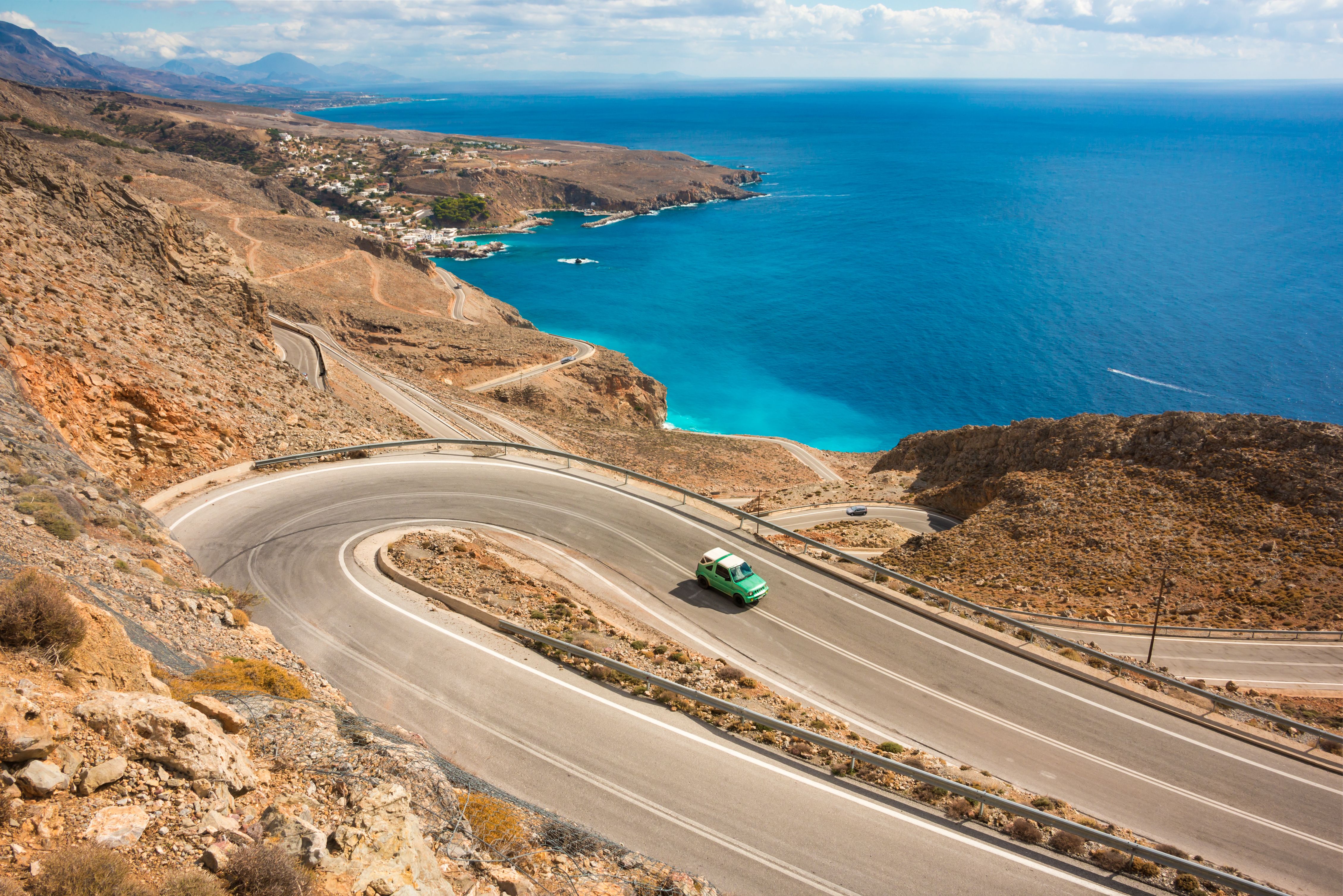 A car driving on a winding coastal road in Crete, Greece