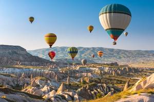 A view of multi-coloured hot air balloons in the sky at sunset in Cappadocia, Turkey