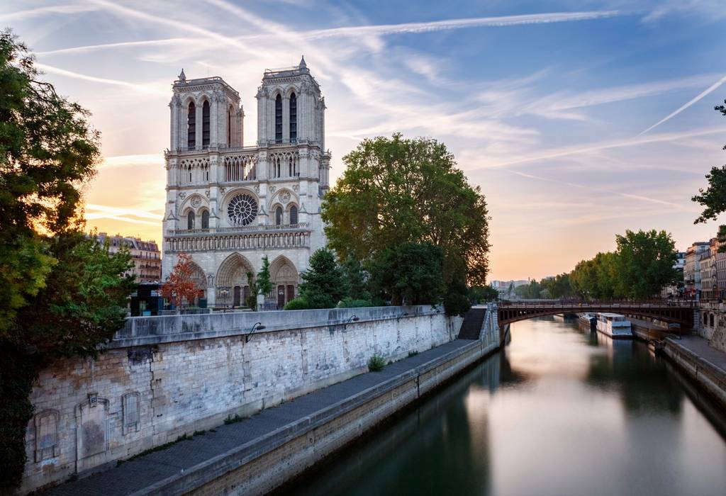 Looking over the Seine at the facade of the Notre Dame cathedral at dawn