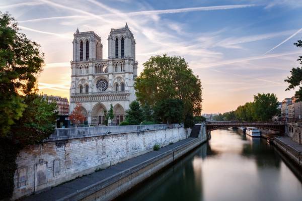 Looking over the Seine at the facade of the Notre Dame cathedral at dawn