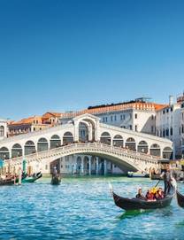 View of the Rialto Bridge spanning the Grand Canal with tourists on gondolier tours
