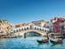 View of the Rialto Bridge spanning the Grand Canal with tourists on gondolier tours