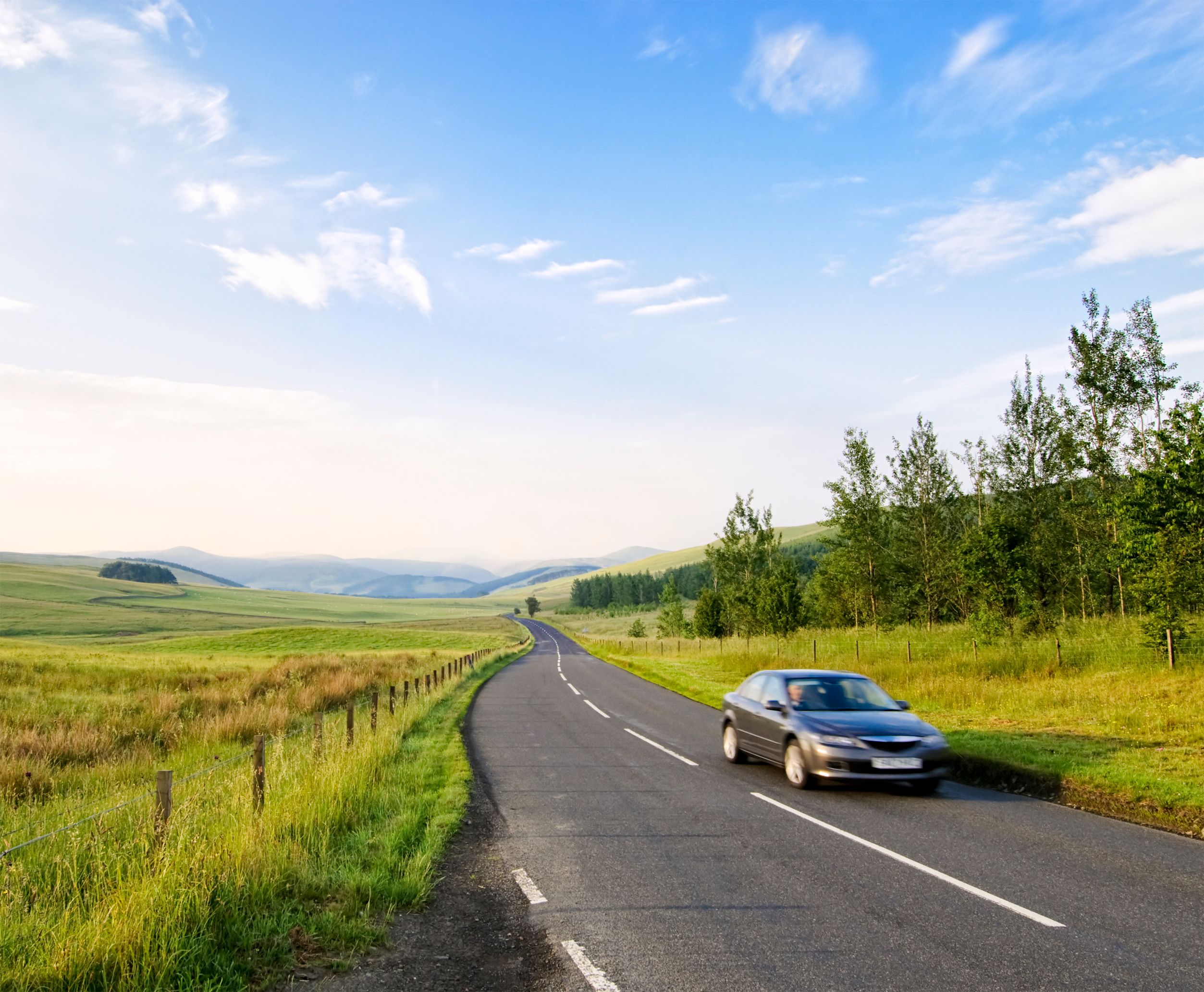 Motion blur on a single car as it speeds along a winding countryside road in the Scottish Borders