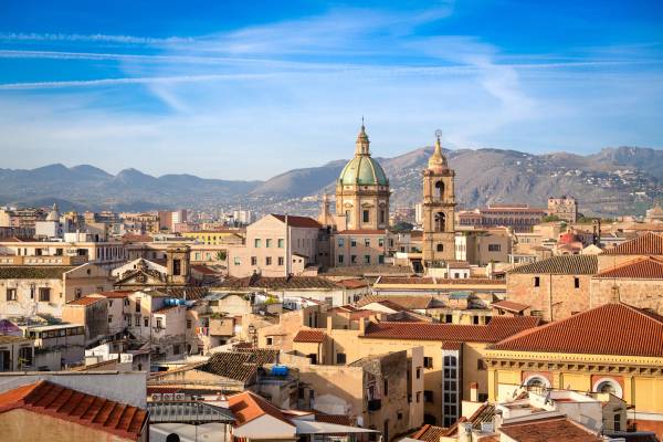 Early morning view of the Palermo skyline with its pastel yellow houses and the dome and bell tower of its cathedral
