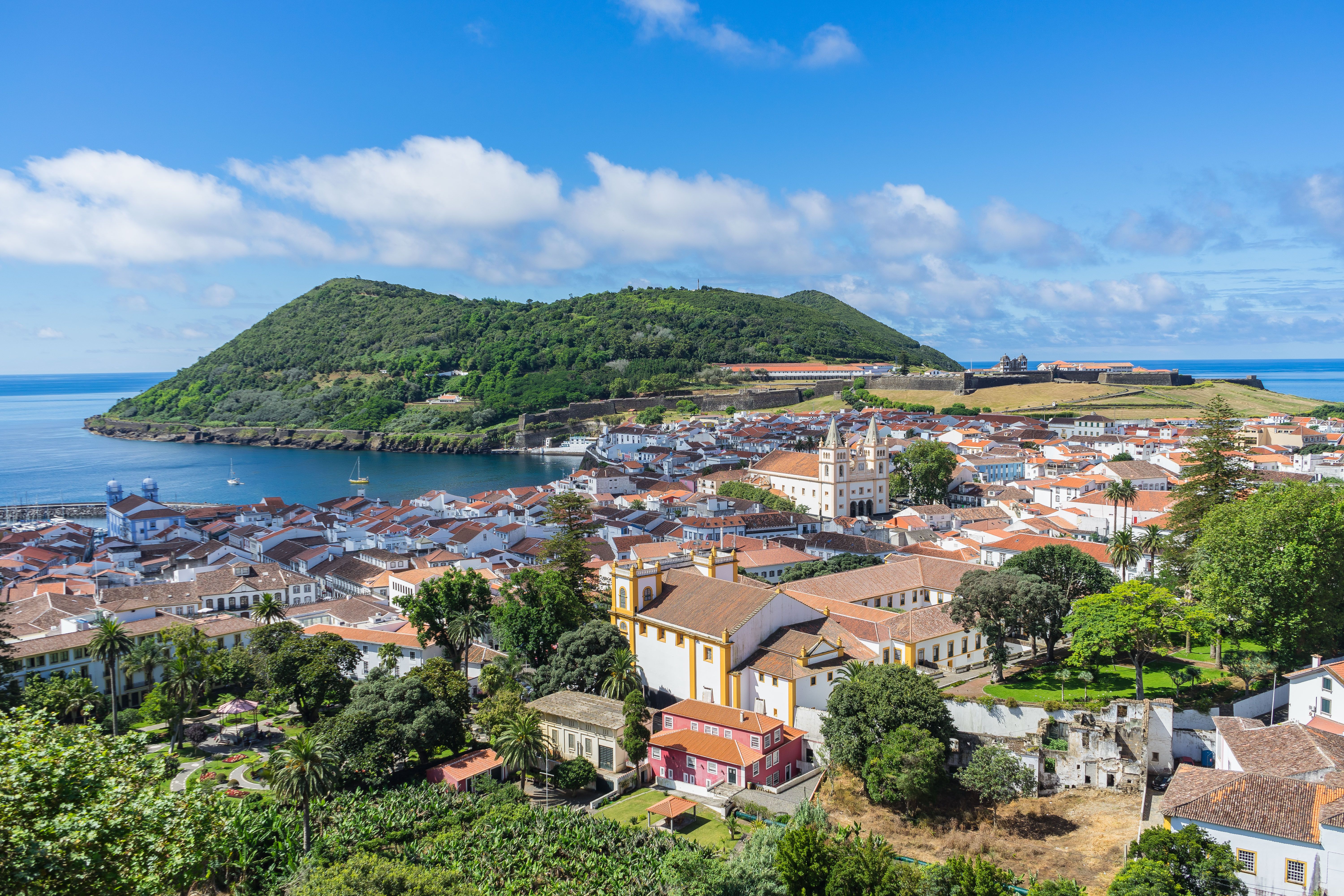 View overlooking a mid-sized seaside town with a large whitewashed church standing tall above the red-roofed houses.