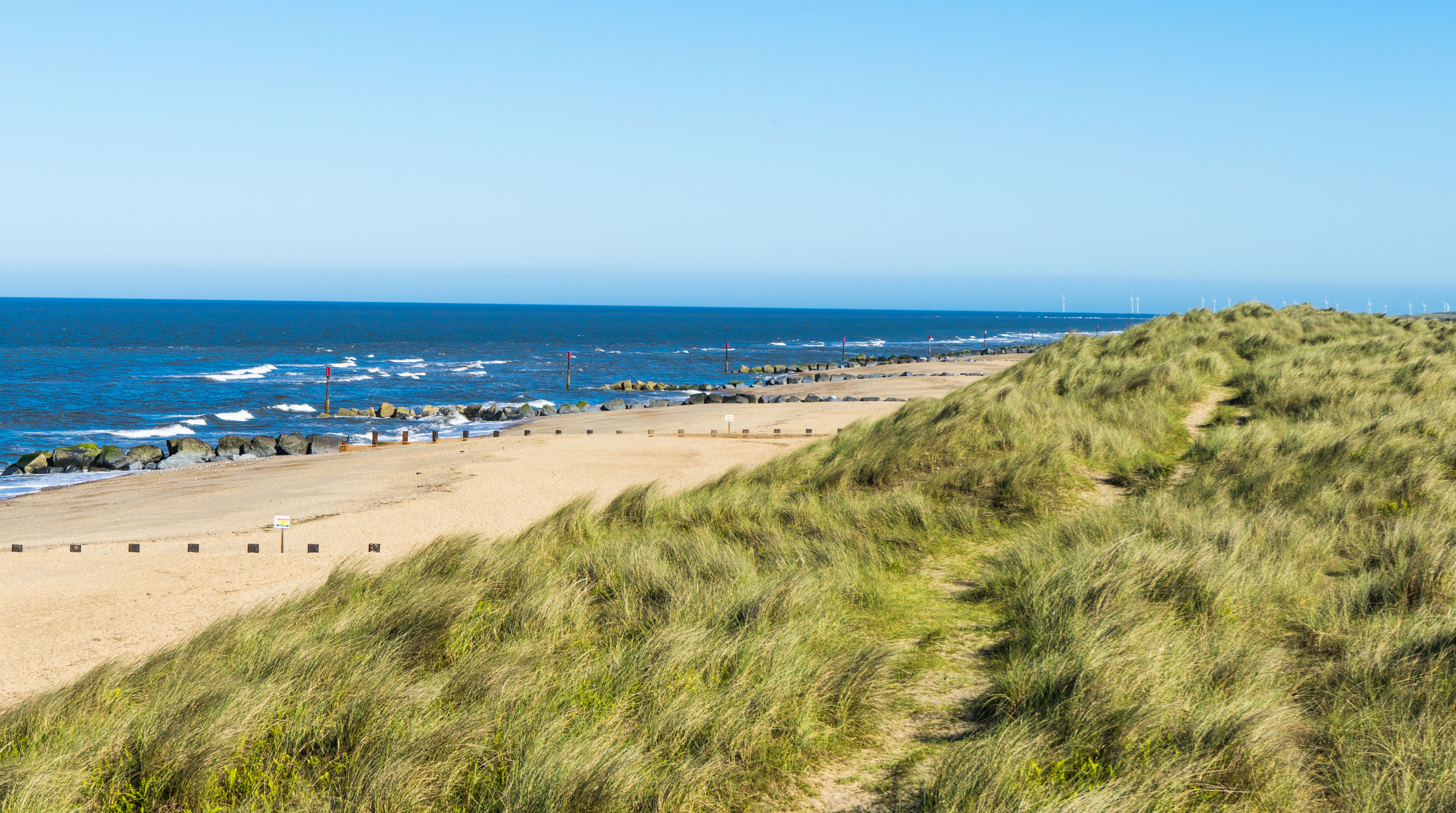 Views from grassy sand dunes out towards an unspoilt golden beach