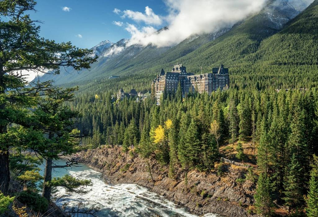 View across the river of Banff Springs Hotel in Alberta, surrounded by pine trees