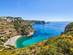 Aerial view of a busy beach surrounded by tall cliffs with boats bobbing off the coast.