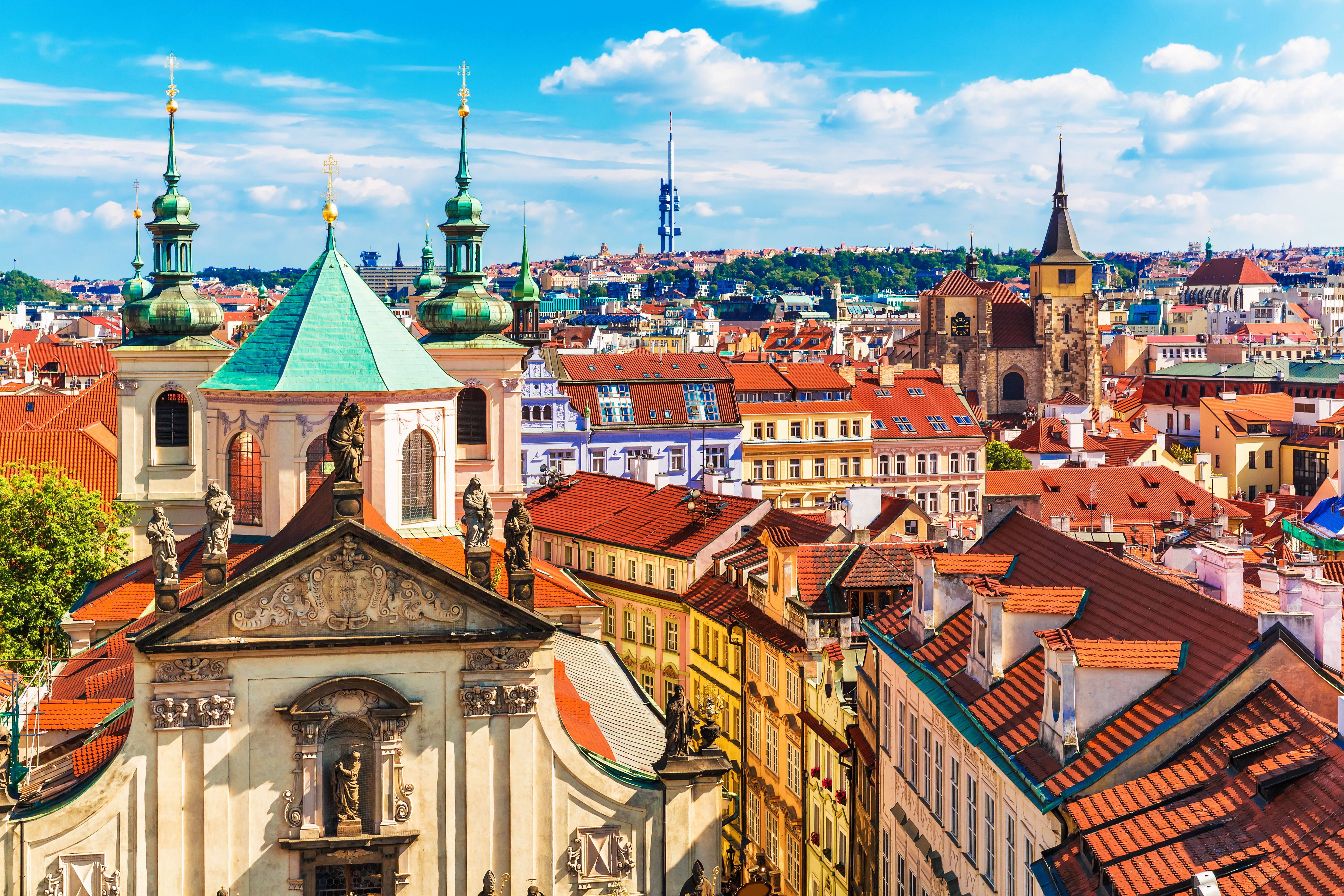 An aerial city view of Prague's terracotta rooftops and colourful buildings on a summer's day