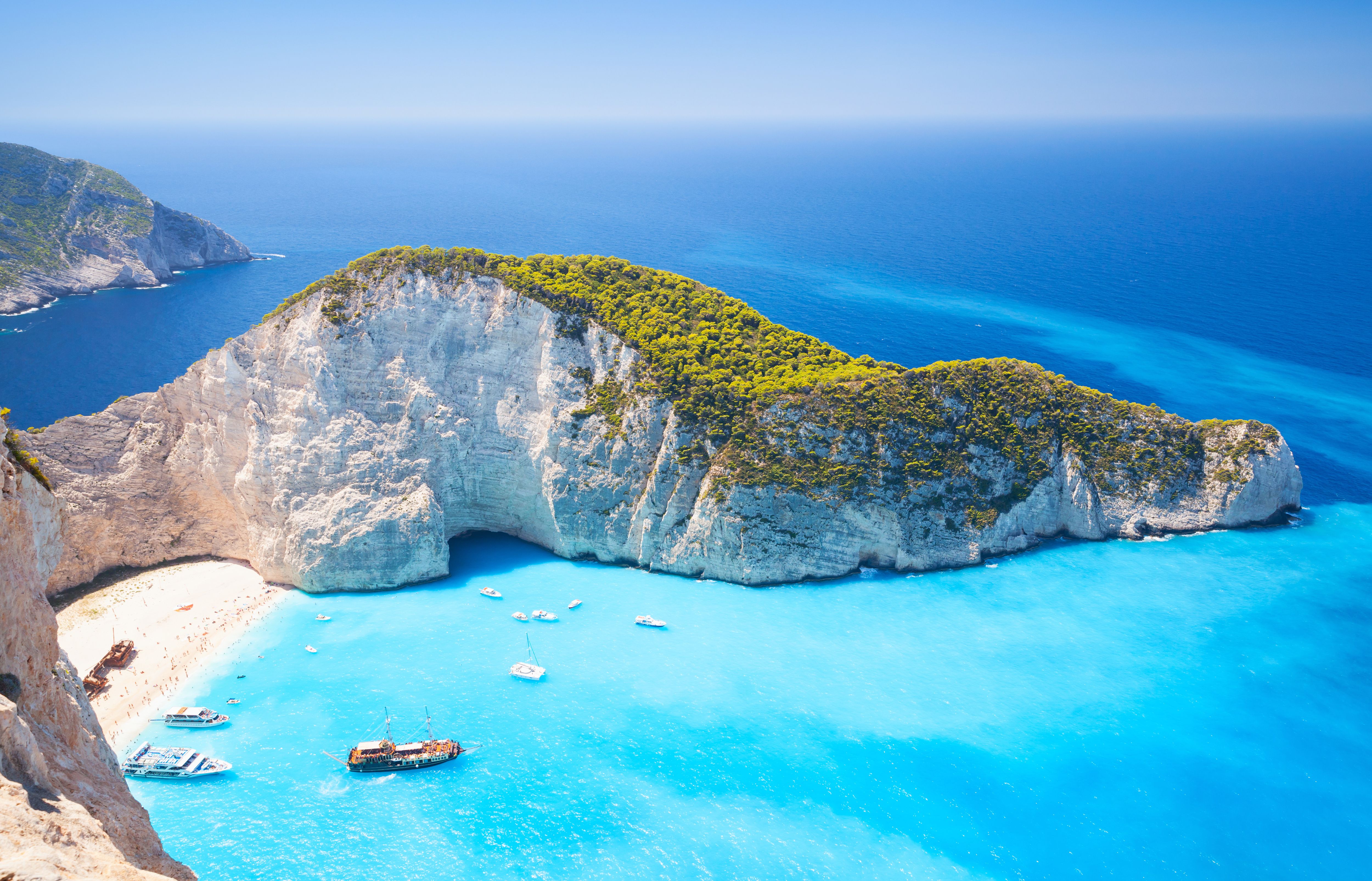 An aerial view on the famous Shipwreck Beach in Zante with boats on sparkling blue water and surrounded by white cliffs covered in green trees