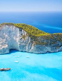 An aerial view on the famous Shipwreck Beach in Zante with boats on sparkling blue water and surrounded by white cliffs covered in green trees