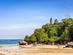 View of a golden, sandy beach with a traditional temple on a cliff overlooking the bay