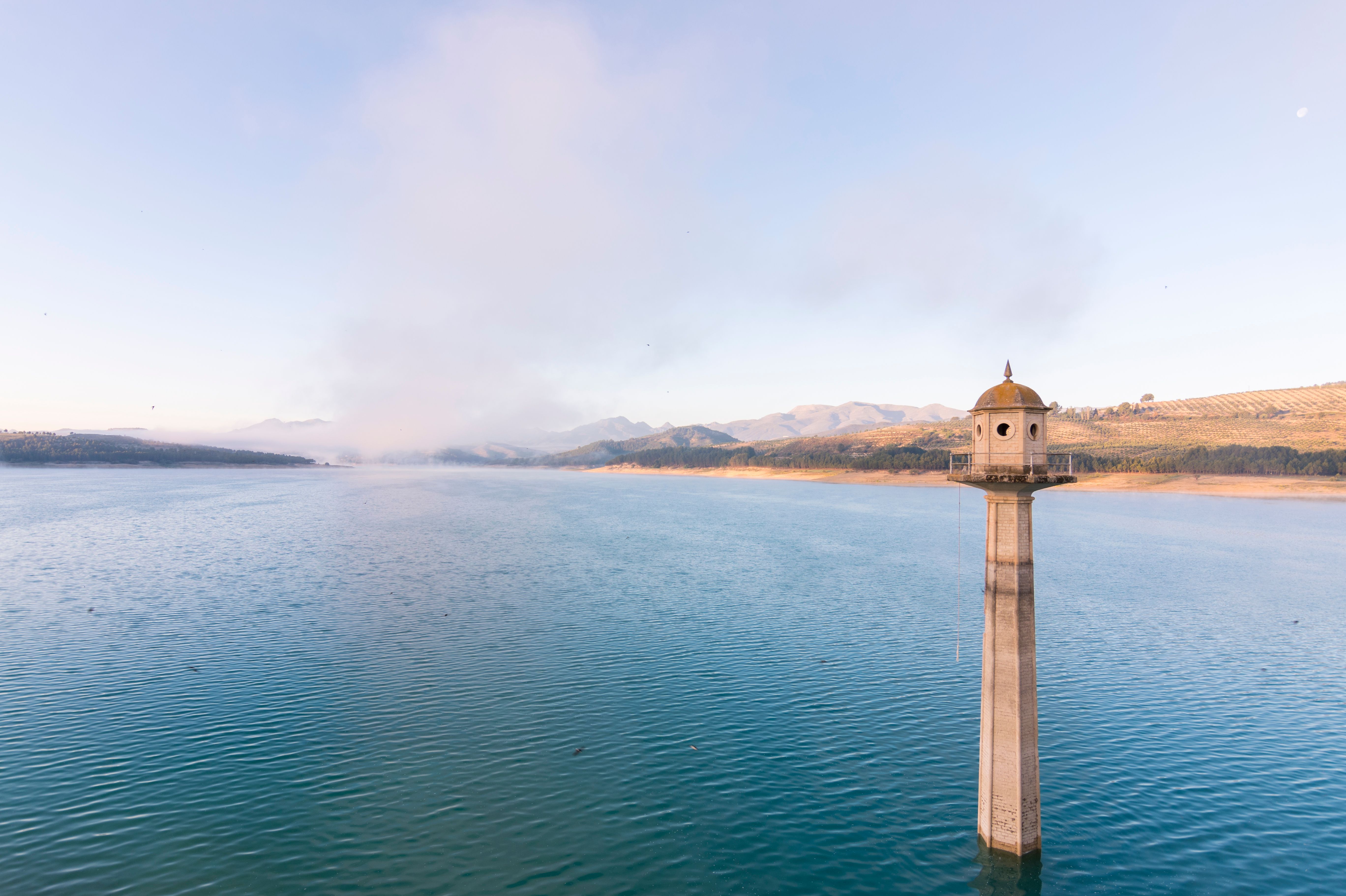 View across a calm lake on a foggy morning.
