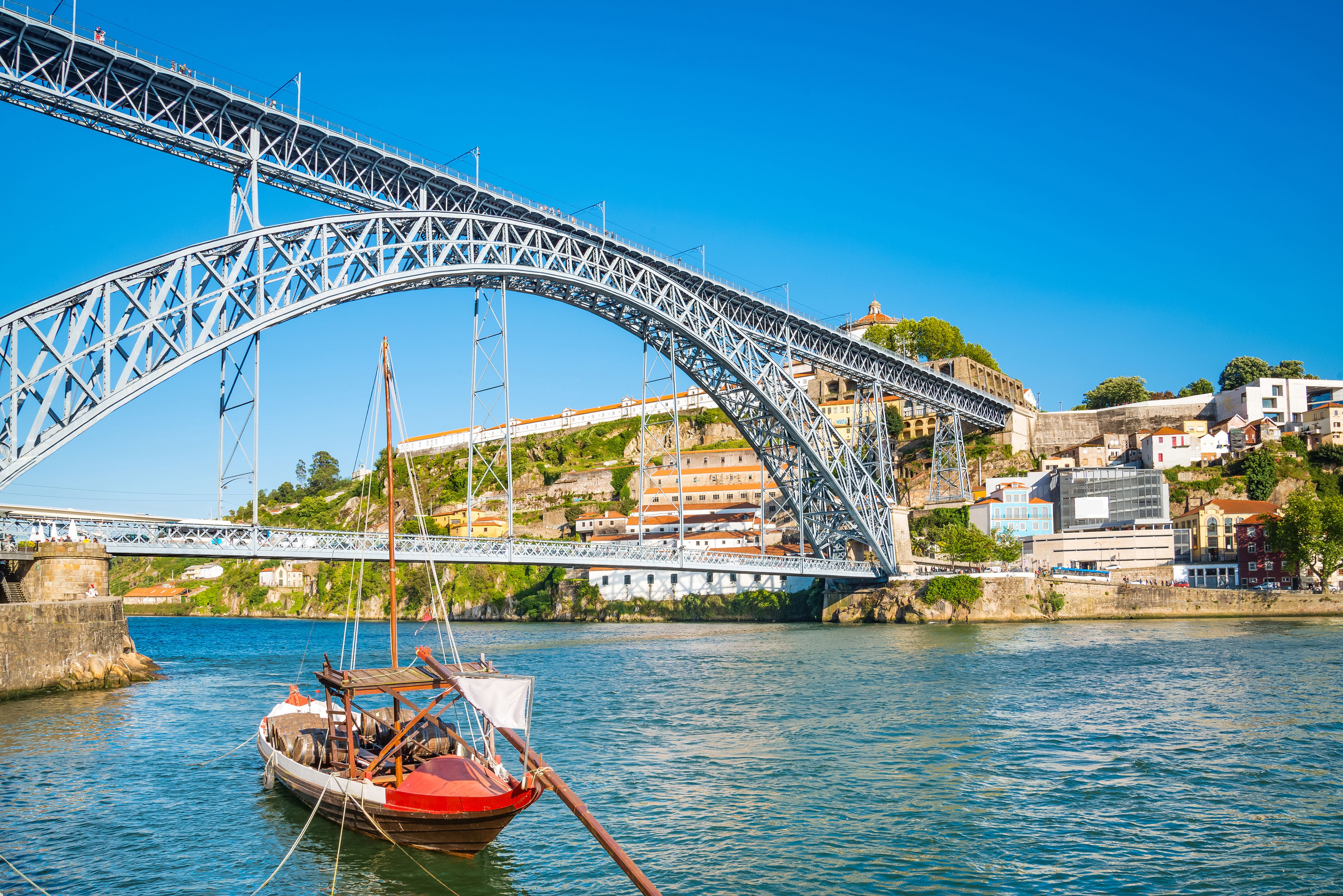 View of the Dom Luis I Bridge in Porto with a traditional wooden sailing boat