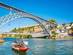 View of the Dom Luis I Bridge in Porto with a traditional wooden sailing boat