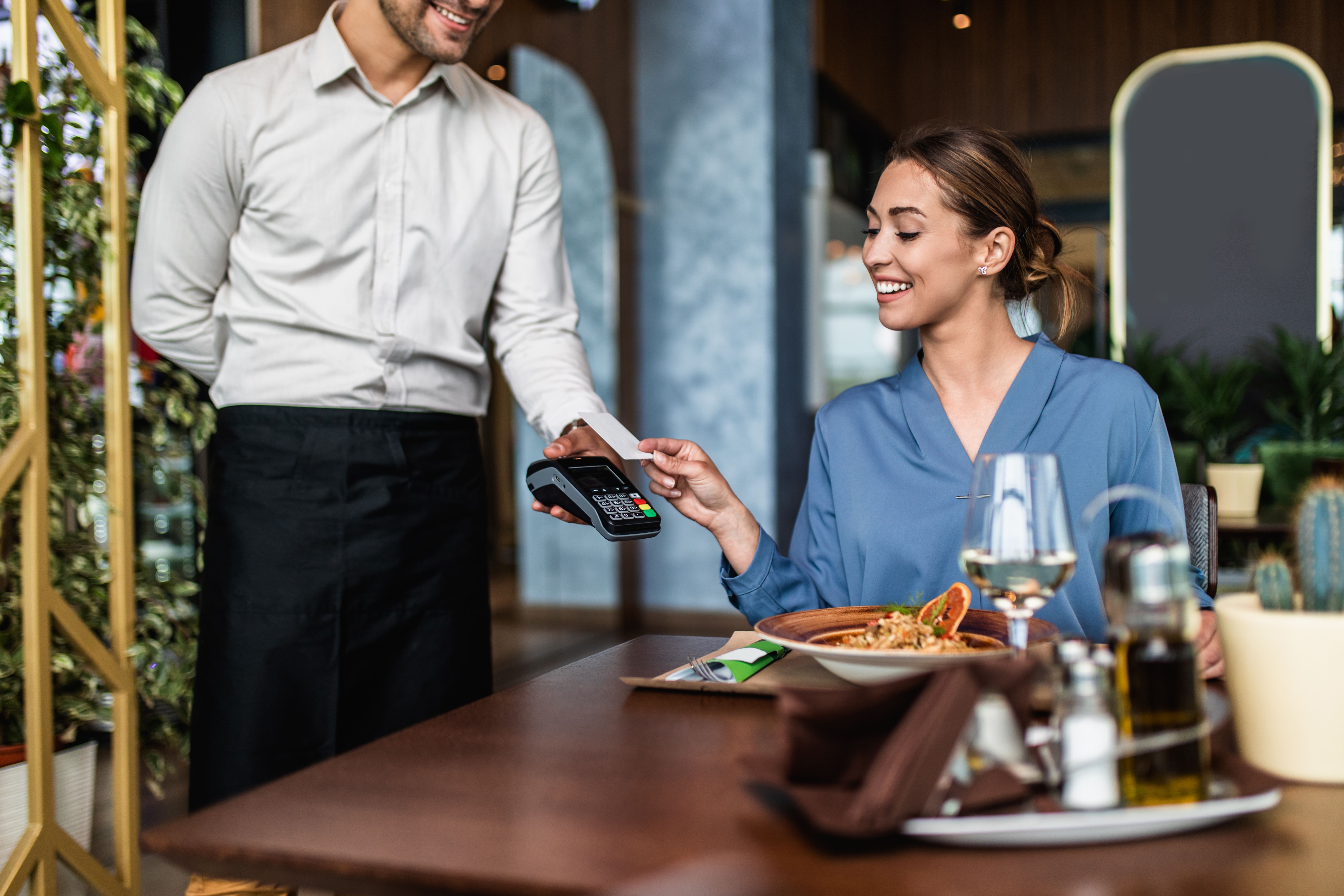 Young woman paying for her order with a credit card in a restaurant.
