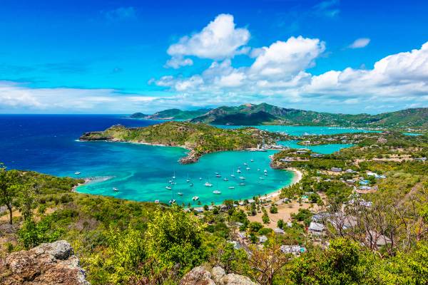 Aerial landscape view of English Harbor in Antigua with yachts bobbing in a sheltered bay and green mountainous islands beyond
