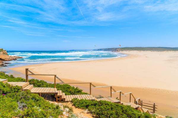 A wooden walkway runs in front of and down to the huge sandy Praia do Bordeira beach in the Algarve