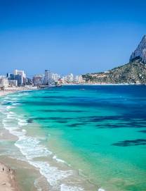 View of the white-sand Calpe Beach with the dramatic Peñon de Ifach rock formation at one end 