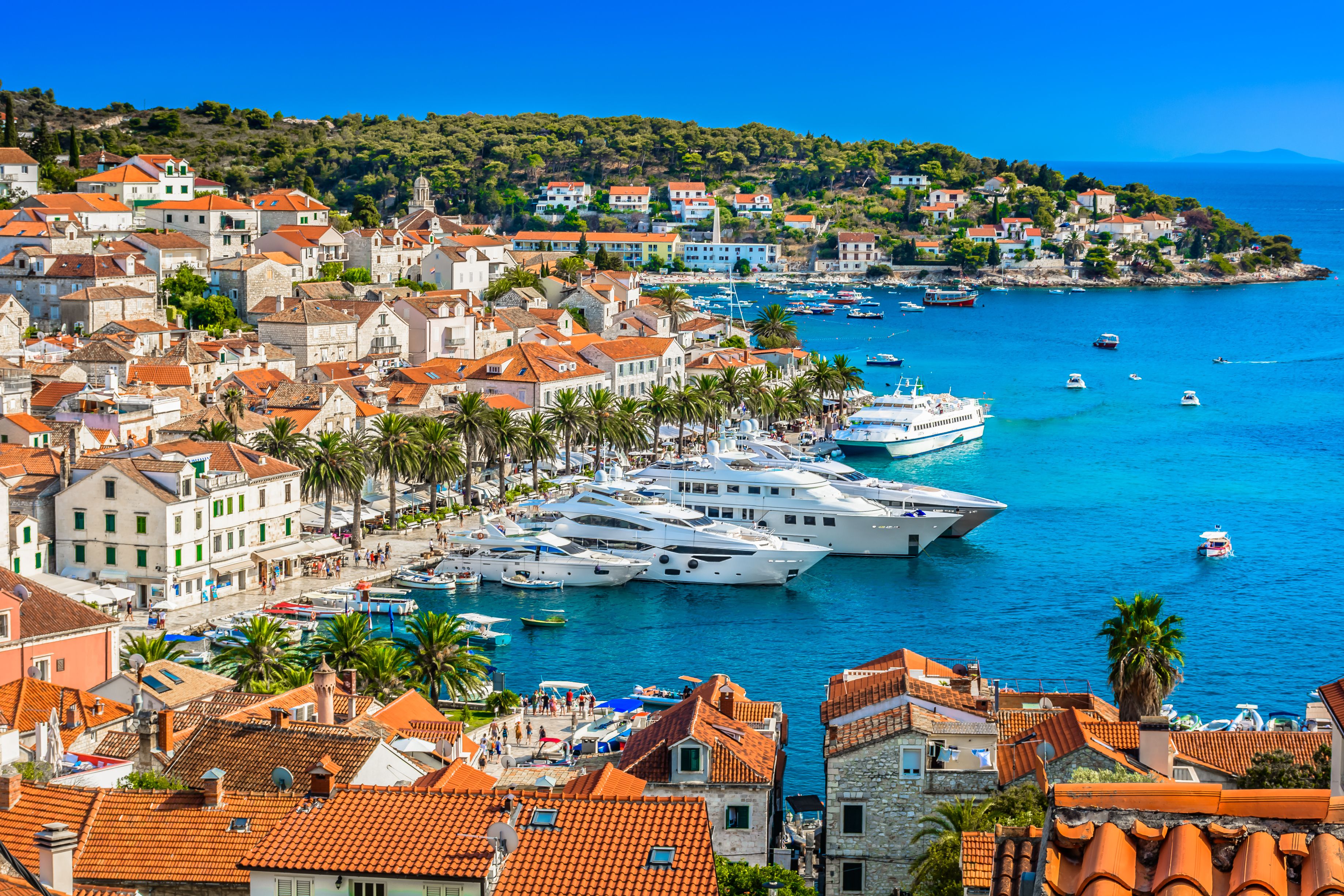 Aerial view of the sandstone-coloured buildings of Hvar Town and luxury super-yachts in the habour.