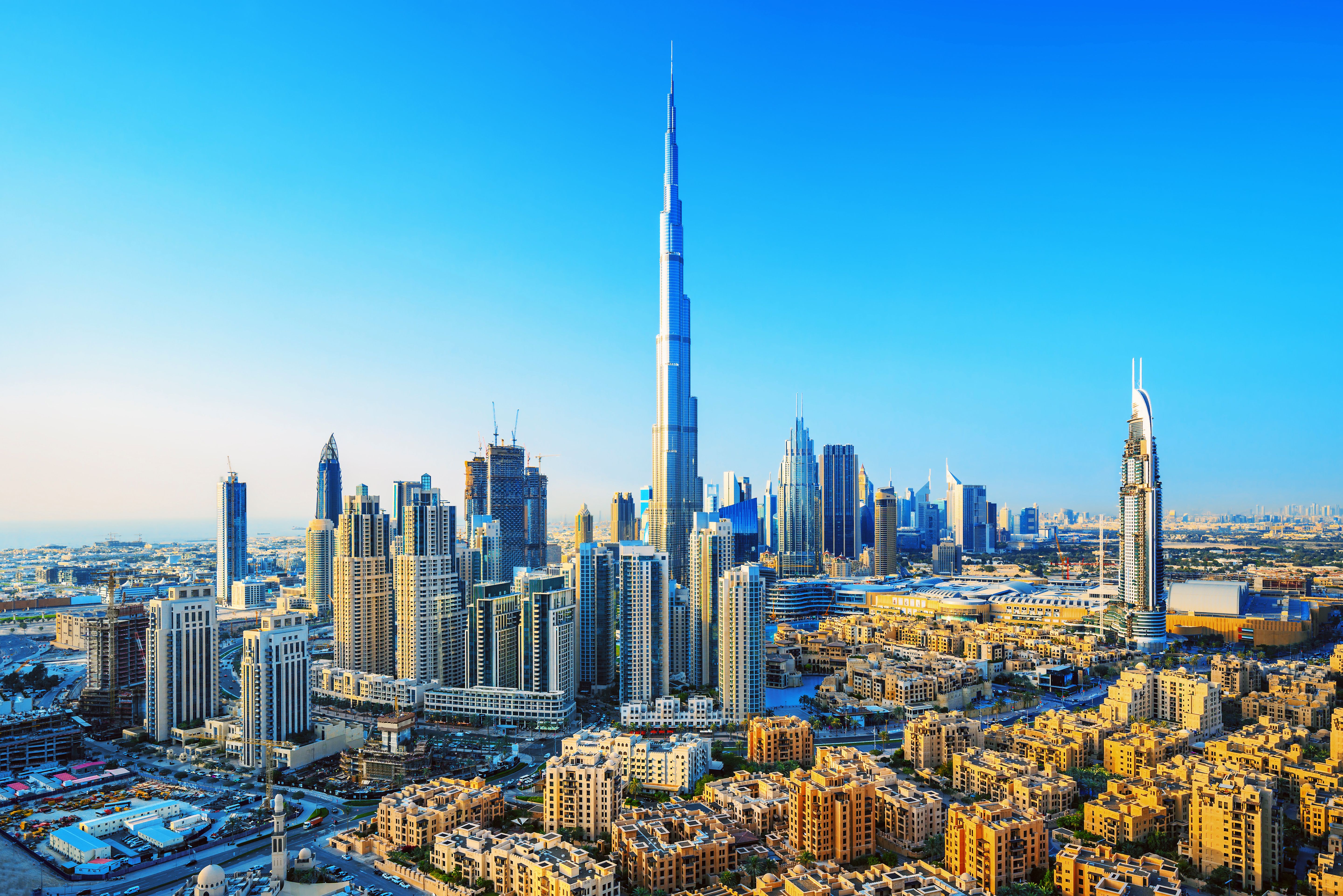 View of the Burj Khalifa in Dubai surrounded by city skyscrapers on a bright blue day