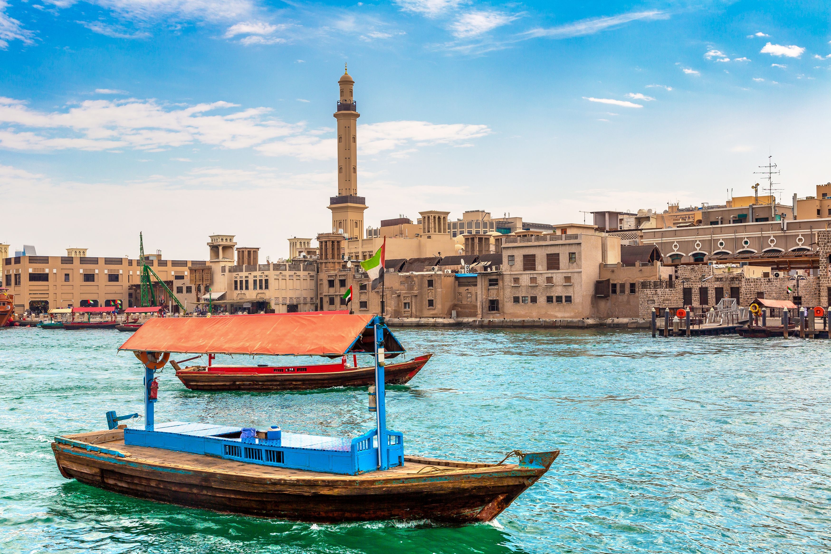 View of a ferry boat in Dubai Creek with ancient buildings in the background on a clear day