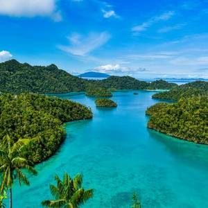 Aerial view of tree-covered islands adrift in the clear, turquoise waters surrounding Indonesia