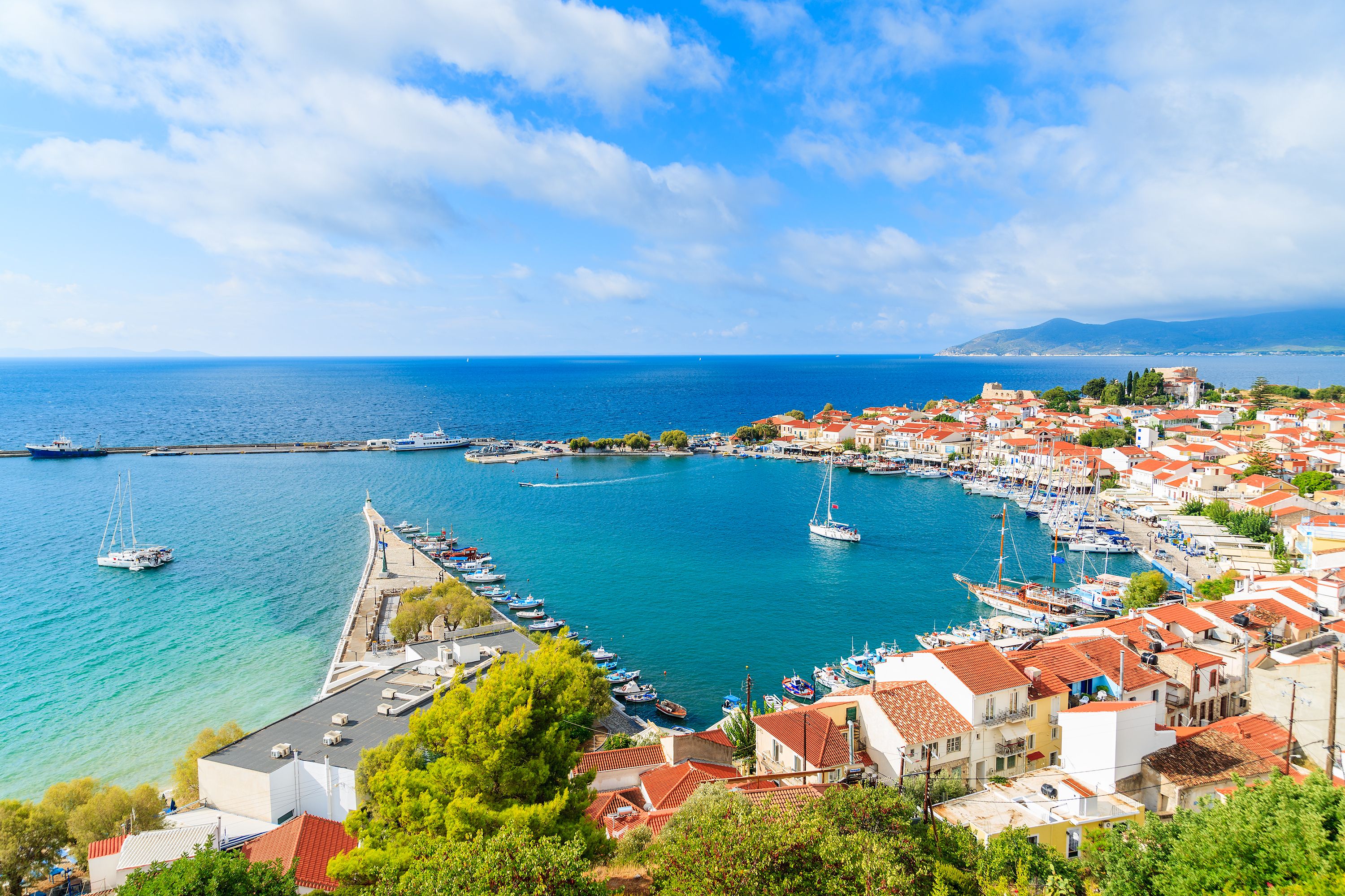 View of a boat-filled port town lined with whitewashed houses in Samos, Greece
