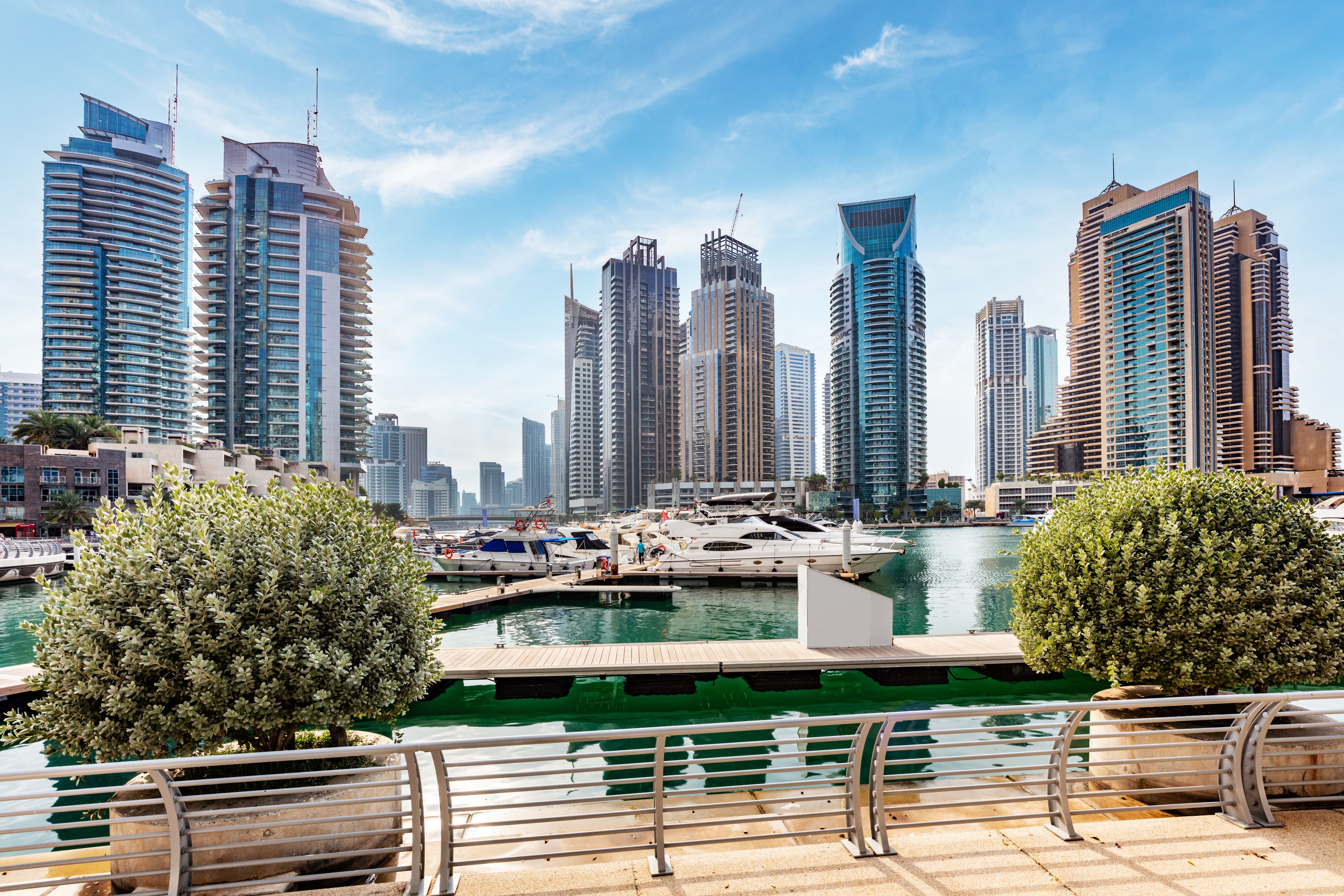 A view from the waterfront promenade of Dubai marina with yachts and skyscraper buildings