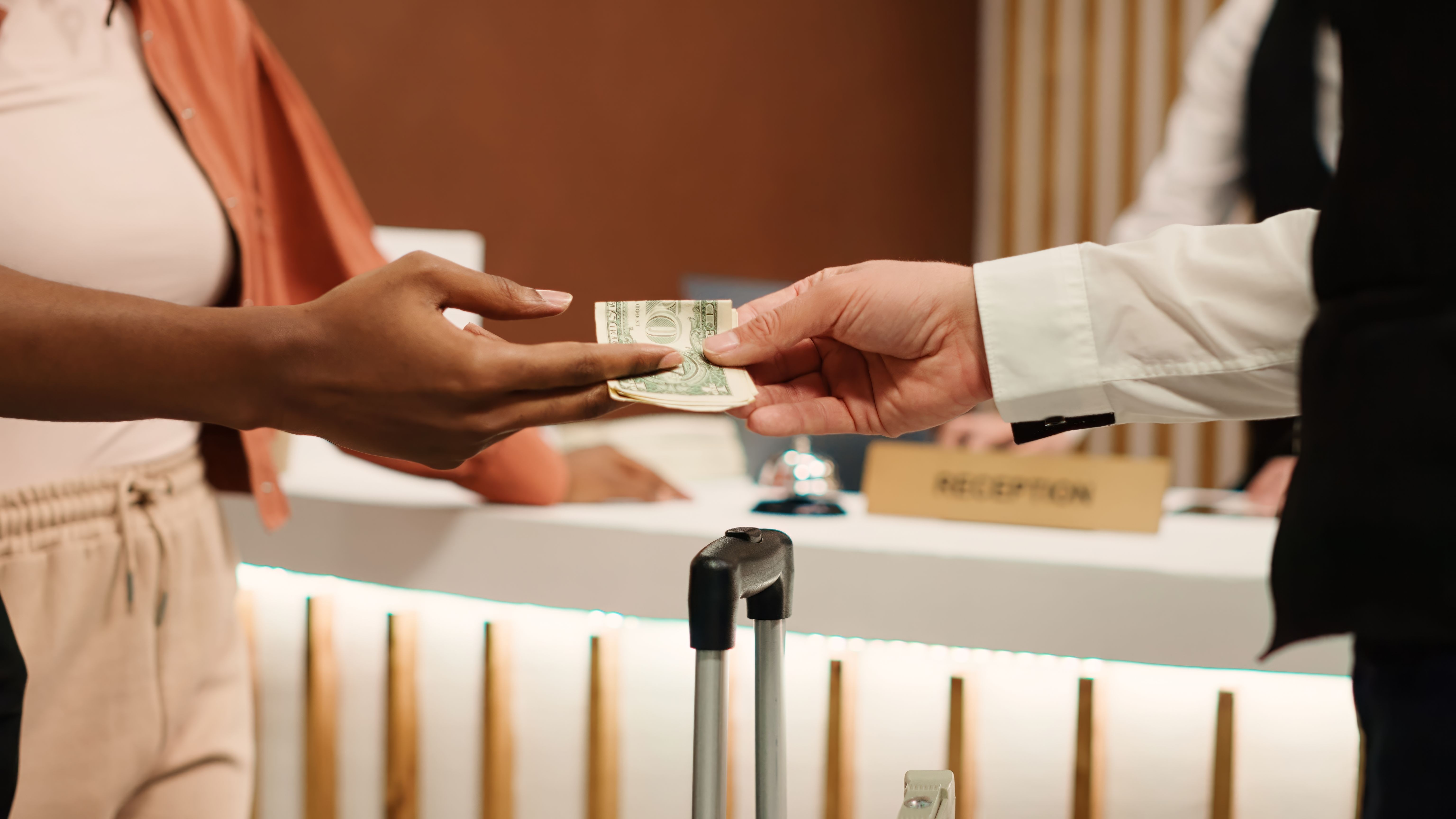 Close up view of a woman tipping a member of hotel staff with cash notes