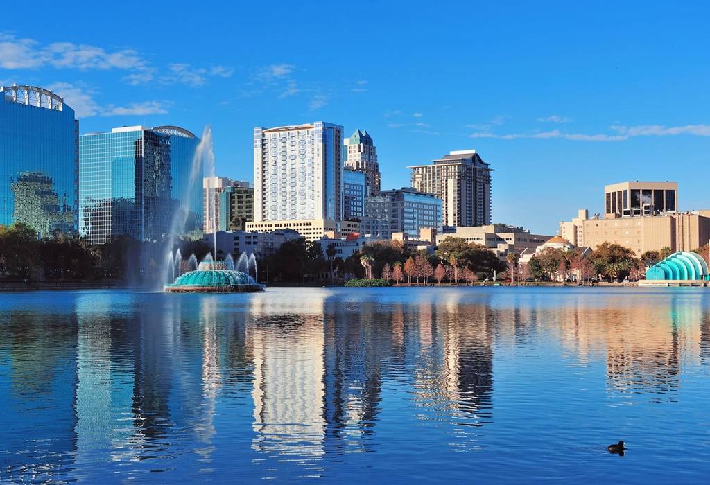 A view of city skyscrapers across Lake Eola in Orlando, Florida on a bright blue day