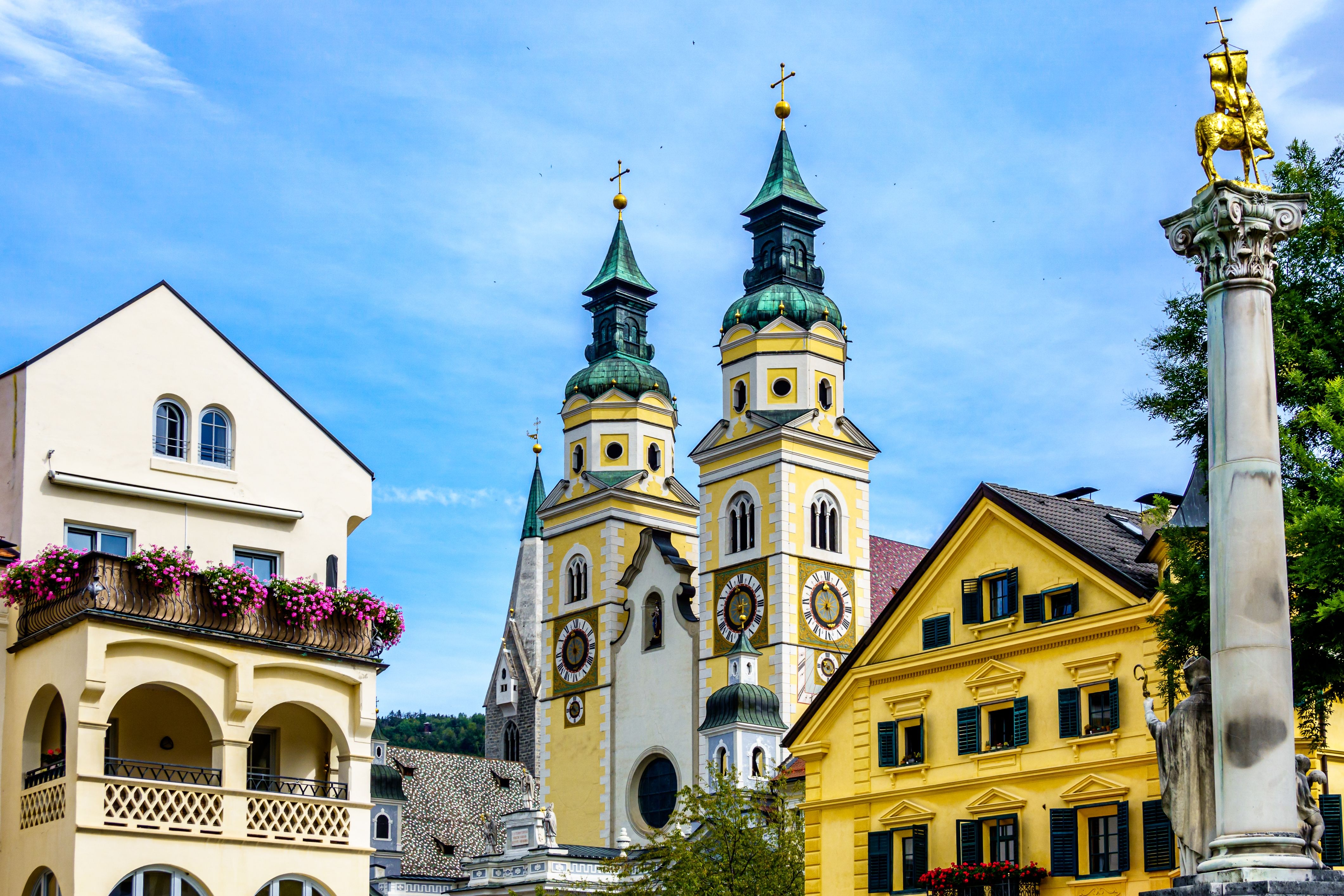 View of a cathedral with two bell towers and other old town buildings in an Italian village.
