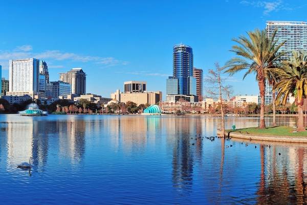 A view across Lake Eola in Orlando, Florida with city skyscrapers in the background on a bright blue day