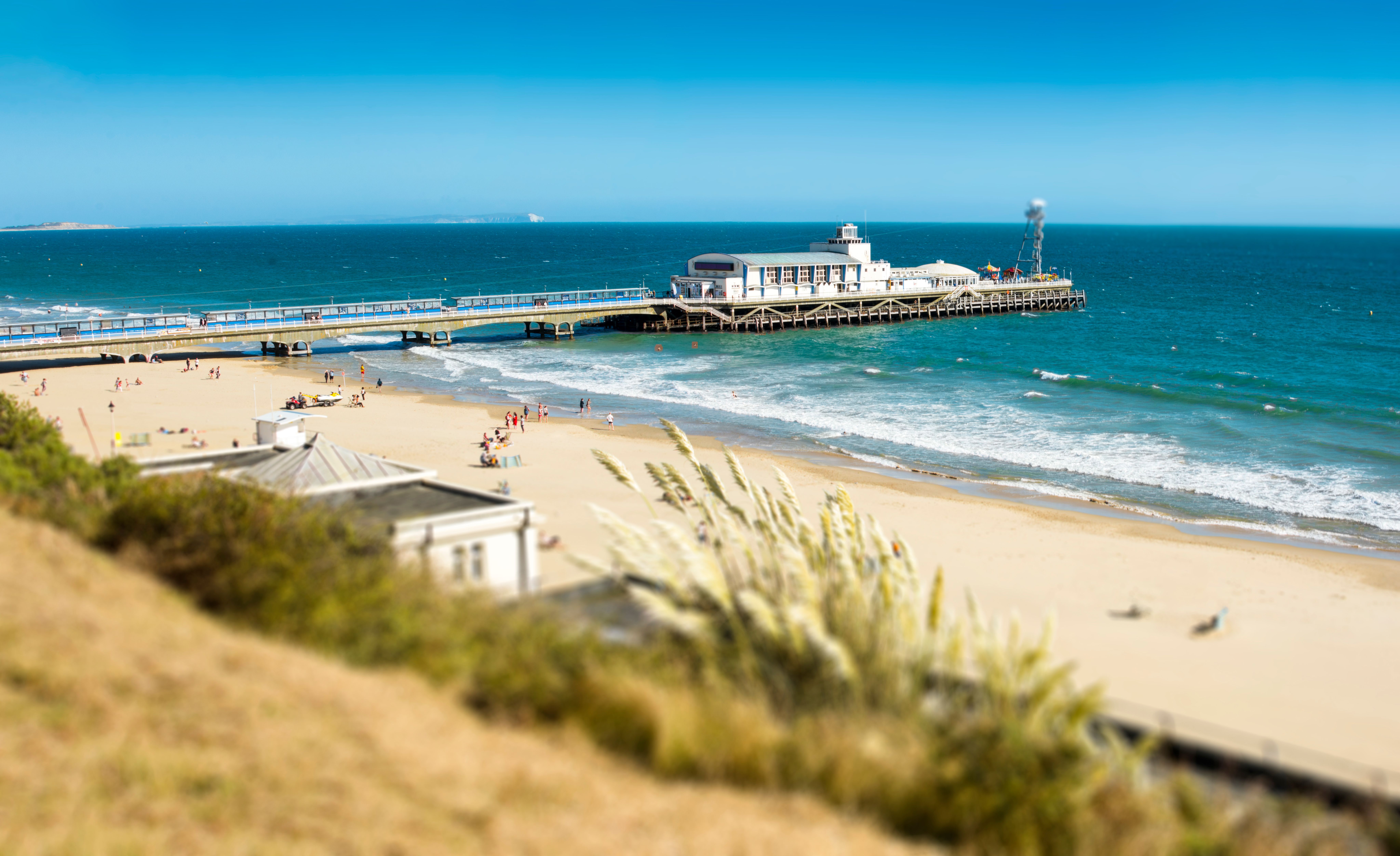 View of golden sands and a long pier from the golden cliffs high above