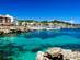 View across the water of Cala Ratjada's harbour and seafront promenade in Majorca