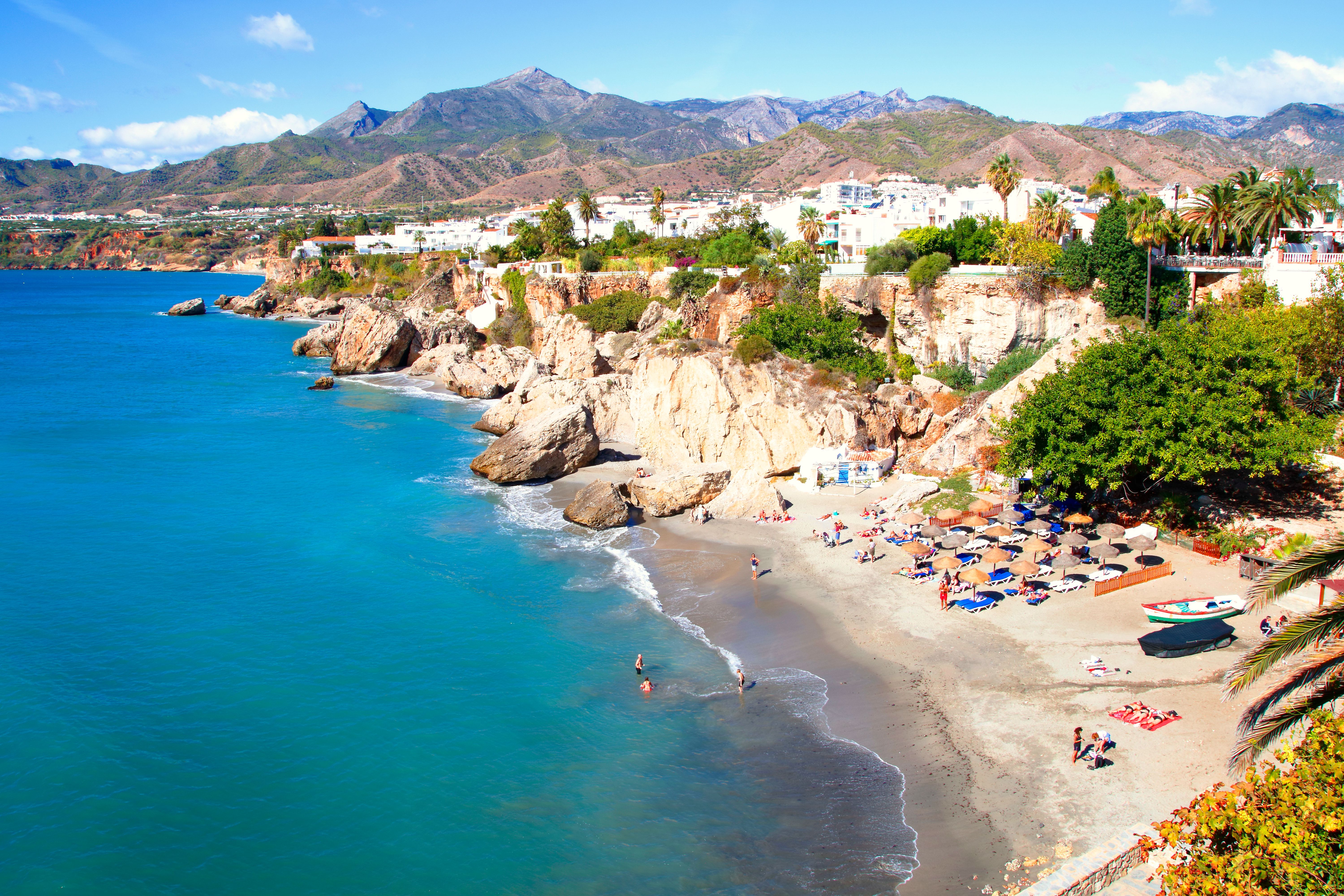 View of a Calahonda beach with the town and mountains of Nerja in the background in Costa del Sol