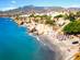 View of a Calahonda beach with the town and mountains of Nerja in the background in Costa del Sol