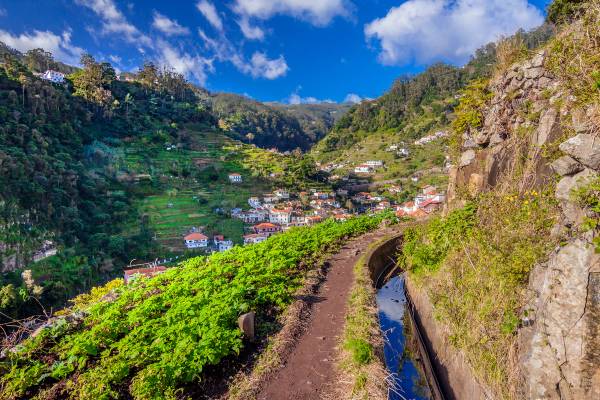 A small path runs alongside an irrigation channel along the mountains of Madeira towards the village of Marocos