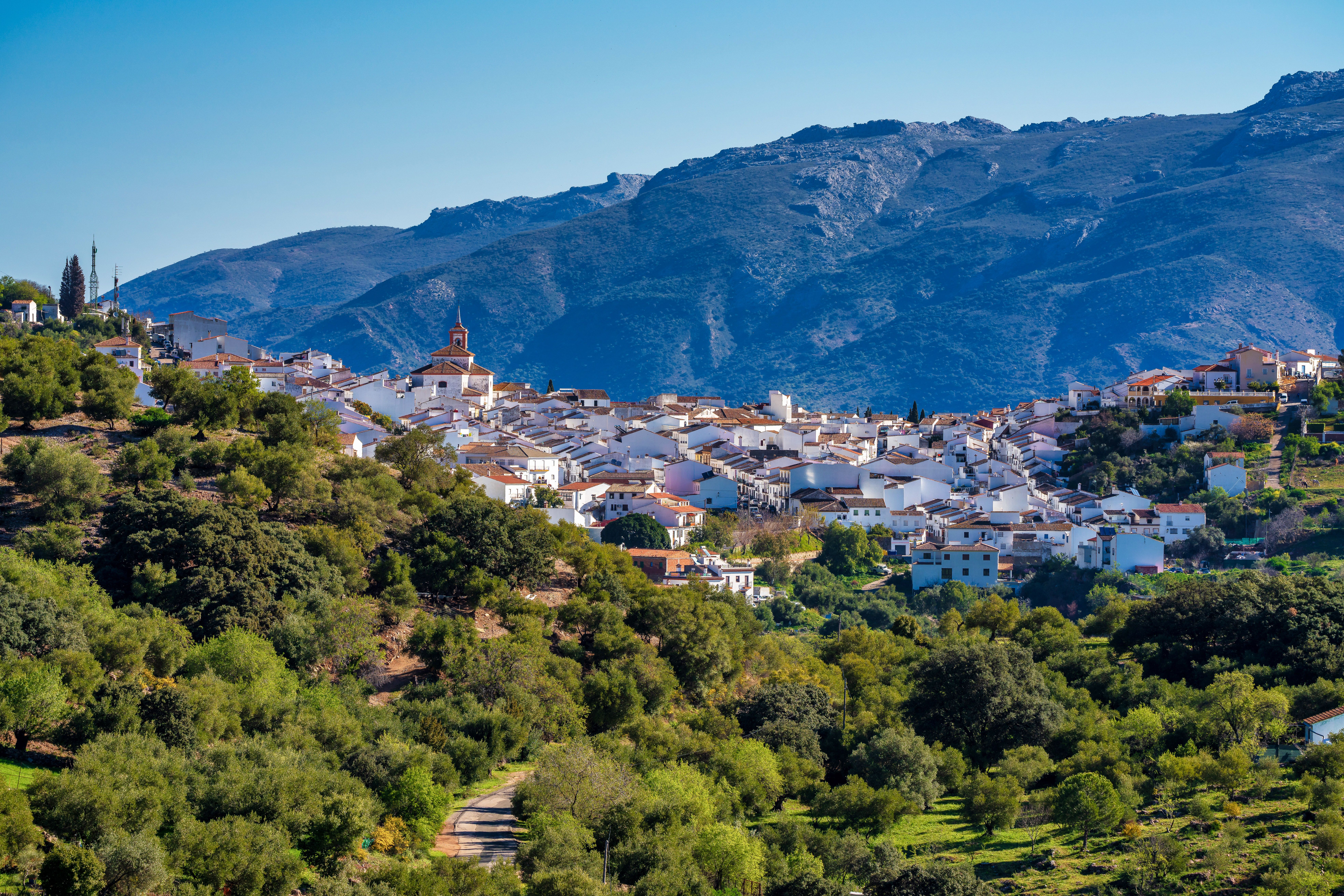 View of a whitewashed town nestled in a lush green valley in Spain.