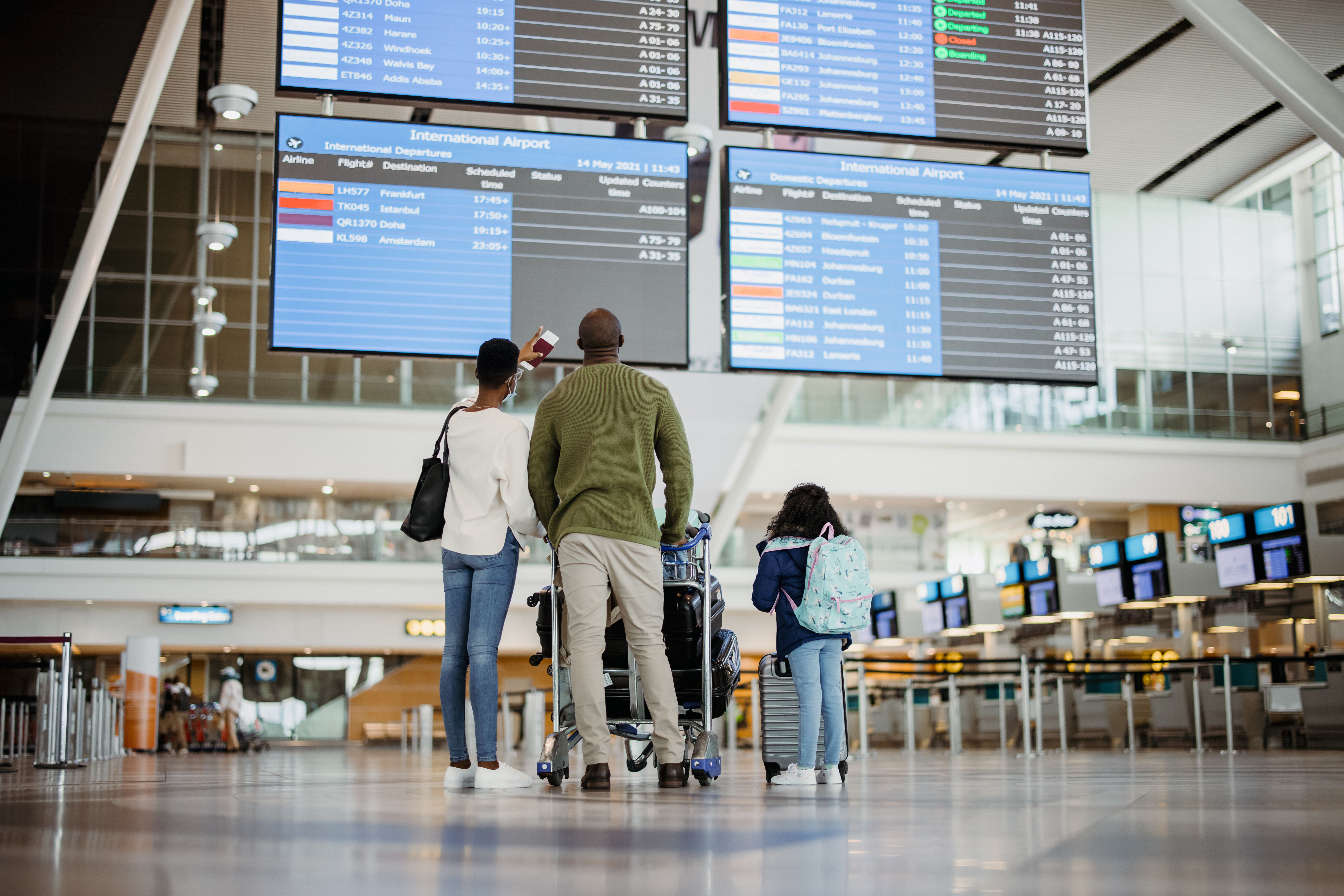 A family stood looking at the display boards in an airport lobby