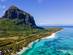 An aerial view of the Le Morne mountain with palm trees, white sand and a clear blue ocean stretching out from the base