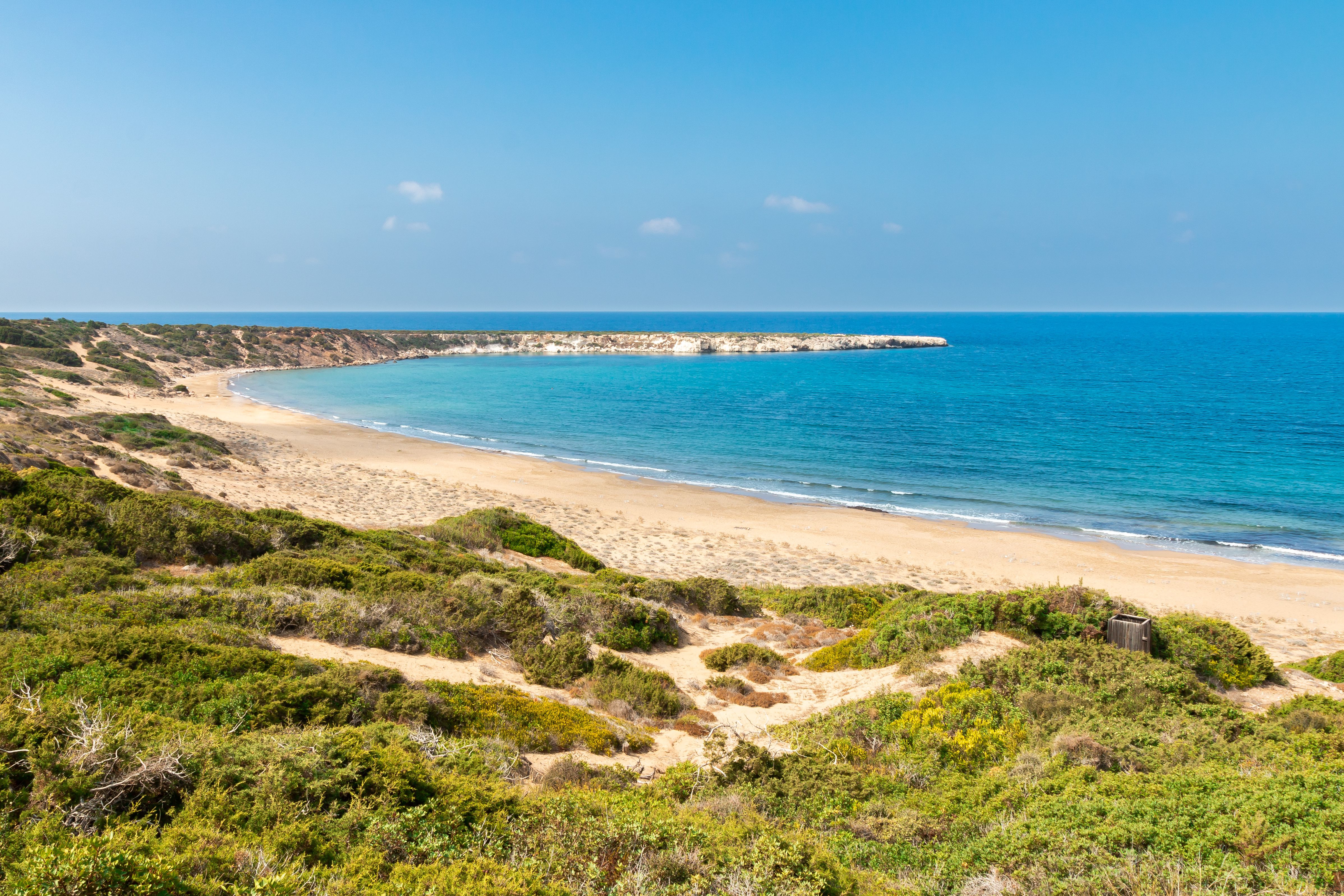View of an empty gold-sand beach on a sunny day.