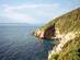 View of a rocky, shrub-covered coastline in the Mediterranean on a sunny day.