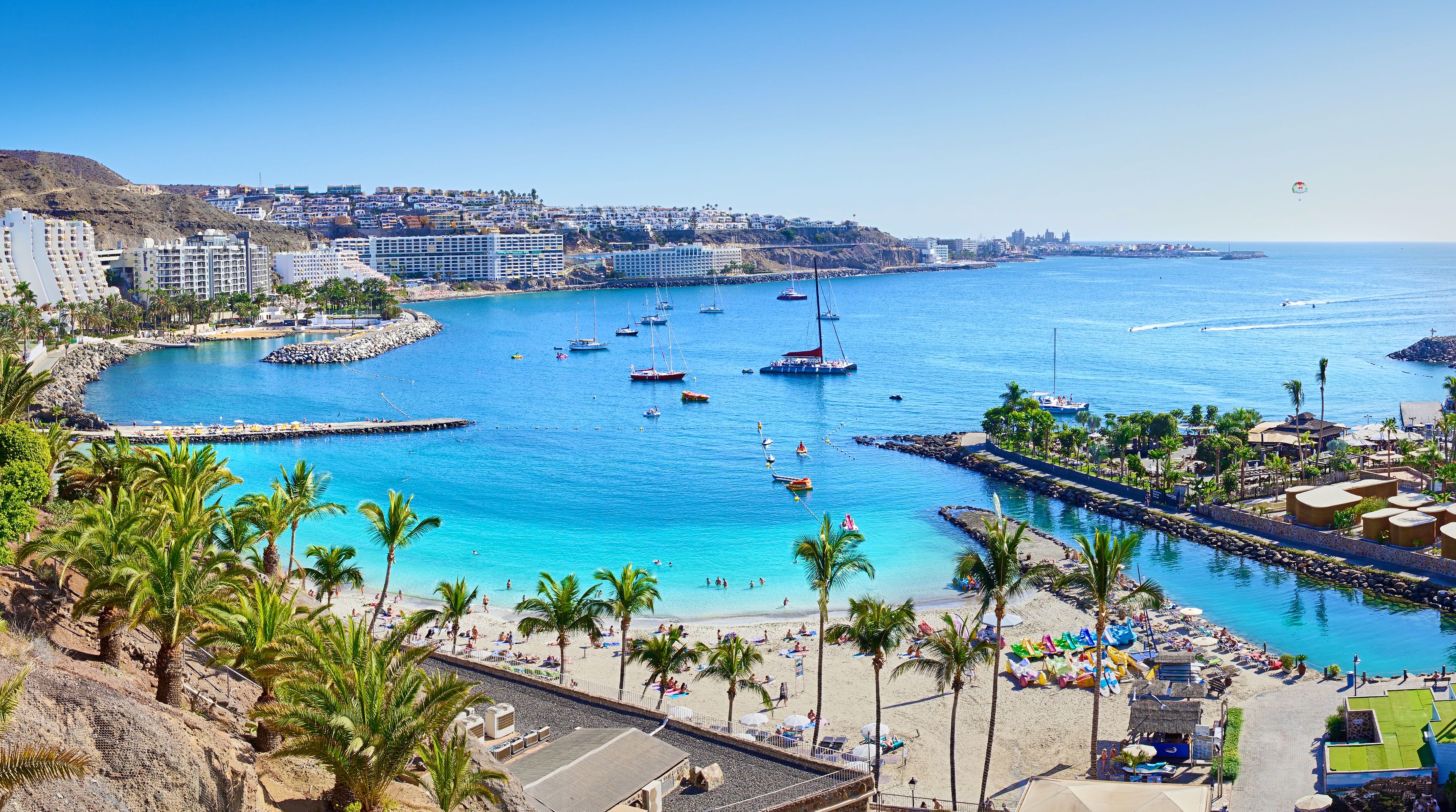 A view of Anfi beach in Gran Canaria with clear blue water and yachts sailing