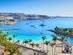 A view of Anfi beach in Gran Canaria with clear blue water and yachts sailing
